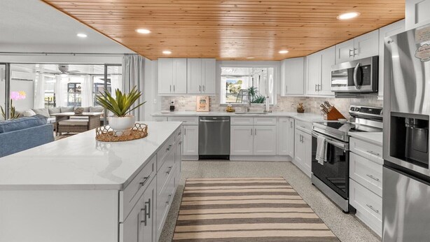 A modern kitchen with white cabinets, stainless steel appliances, and a wooden ceiling. - Large Game Room • Kayaks • No Steps • Waterfront (Crystal River)