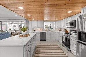 A modern kitchen with white cabinets, stainless steel appliances, and a wooden ceiling. - Large Game Room • Kayaks • No Steps • Waterfront (Crystal River)