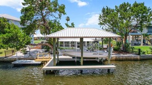 A docked boat with a covered seating area, surrounded by water and greenery. - Large Game Room • Kayaks • No Steps • Waterfront (Crystal River)