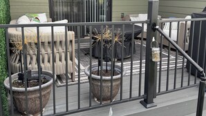 A covered outdoor patio with a seating area, potted plants, and a railing. - Charming 3-bedroom townhome in Sturgis bordering the Black Hills (Sturgis)