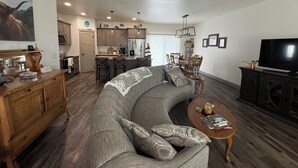 A modern living room with a large gray sectional sofa, a wooden coffee table, and a flat-screen TV. - Charming 3-bedroom townhome in Sturgis bordering the Black Hills (Sturgis)