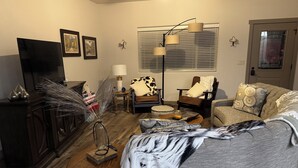 A living room with a sofa, armchairs, a coffee table, a TV, and a fireplace. - Charming 3-bedroom townhome in Sturgis bordering the Black Hills (Sturgis)