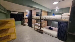 A bunk bed room with a ladder, a small table, and a yellow crate. - Glur Hostel Pattaya Walking Street (Pattaya)