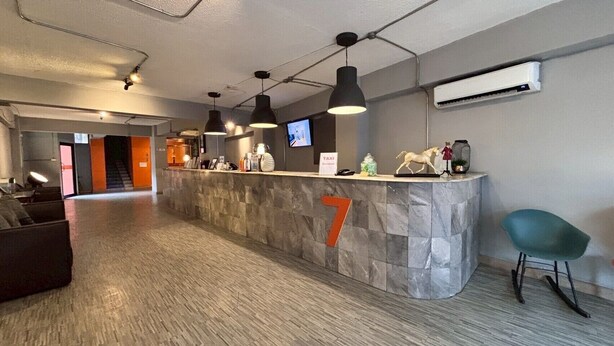 A reception area with a stone counter, a TV, and a number 7 sign. - Glur Hostel Pattaya Walking Street (Pattaya)