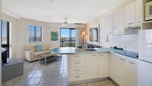 Een moderne keuken met witte kastjes, een inbouw eiland met een spoelbak en uitzicht op de omgeving.