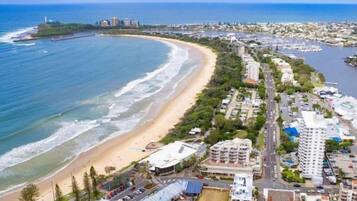 Vista aérea de una ciudad costera con playa, edificios residenciales y un puerto deportivo.