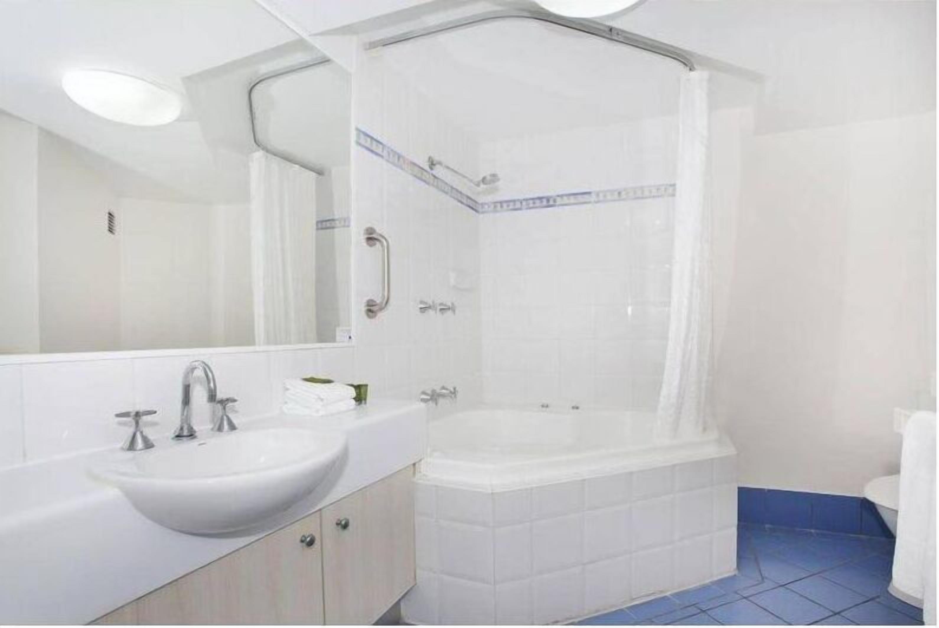 A modern bathroom with a white sink, mirror, and bathtub.