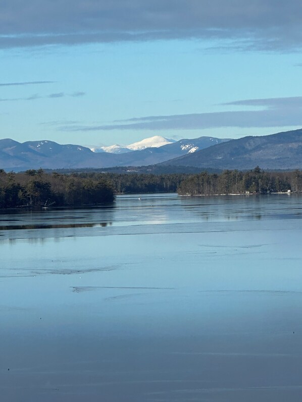 A calm lake with mountains in the background and a forested shoreline.