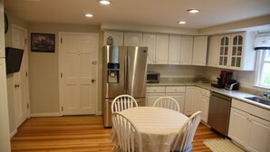 A kitchen with white cabinets, a stainless steel refrigerator, a microwave, and a dishwasher.