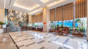 A spacious lobby with a check-in counter, seating area, and large windows.