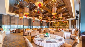A spacious dining area with round tables, beige chairs, and a patterned carpet.
