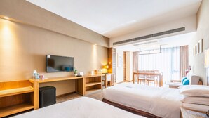 A hotel room with two beds, a desk, a TV, and a small fridge.