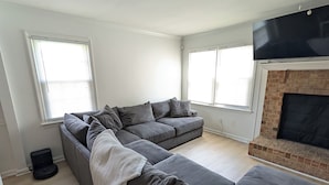 Ein Wohnzimmer mit Ecksofa, Kamin und Deckenventilator.