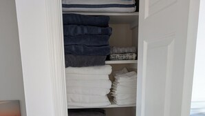 Ein Schrank mit ordentlich gefalteten Handtüchern in verschiedenen Farben und einer Revlon-Box auf dem Boden.