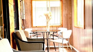 Un patio acogedor con mobiliario de mimbre, una mesa de comedor y un jarrón con flores secas.
