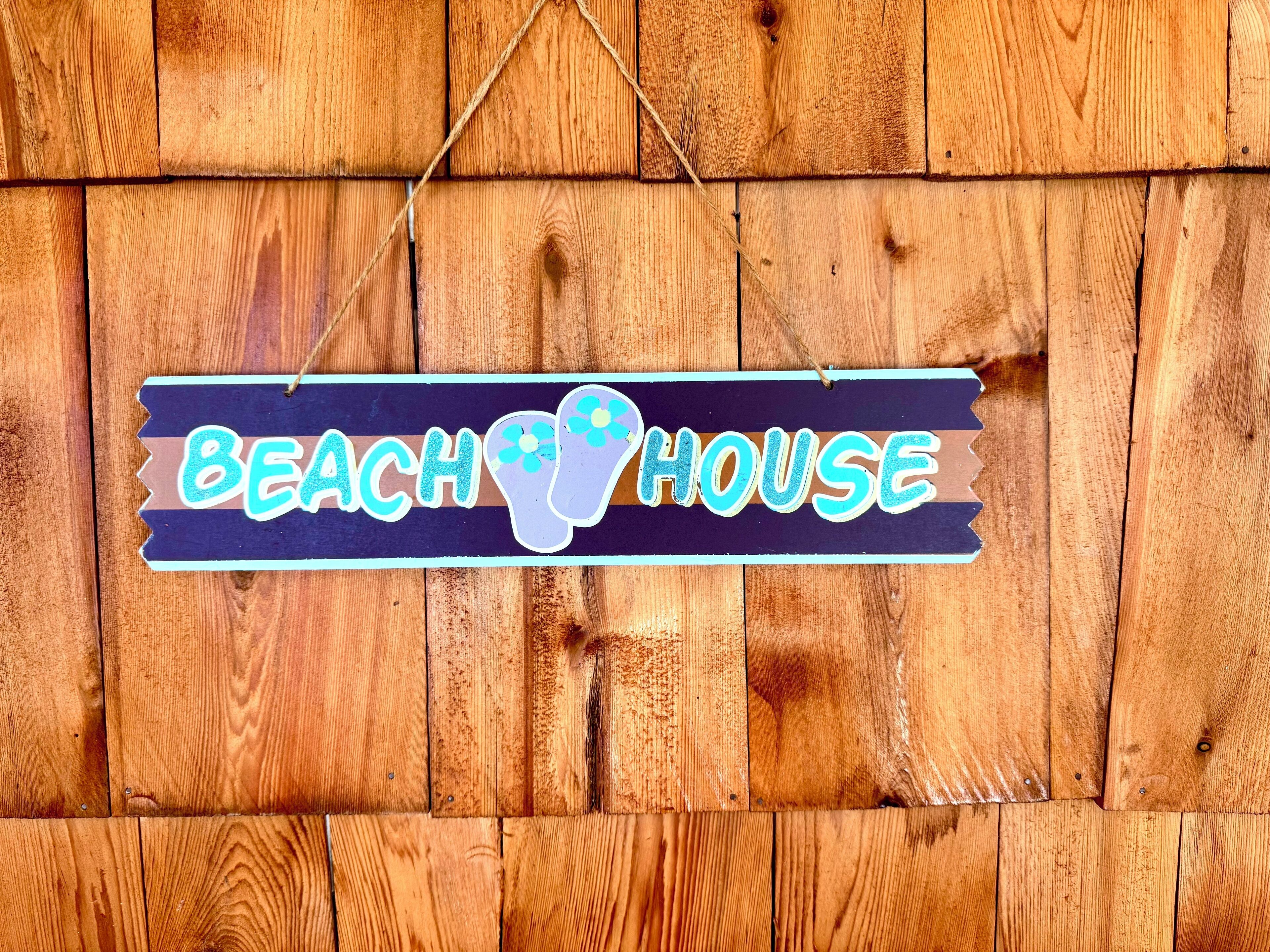 Pared de madera con un letrero que dice 'Beach House'.
