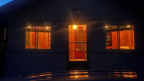 Un edificio con tres ventanas iluminadas y una puerta, que muestra el número '4062' sobre la puerta.