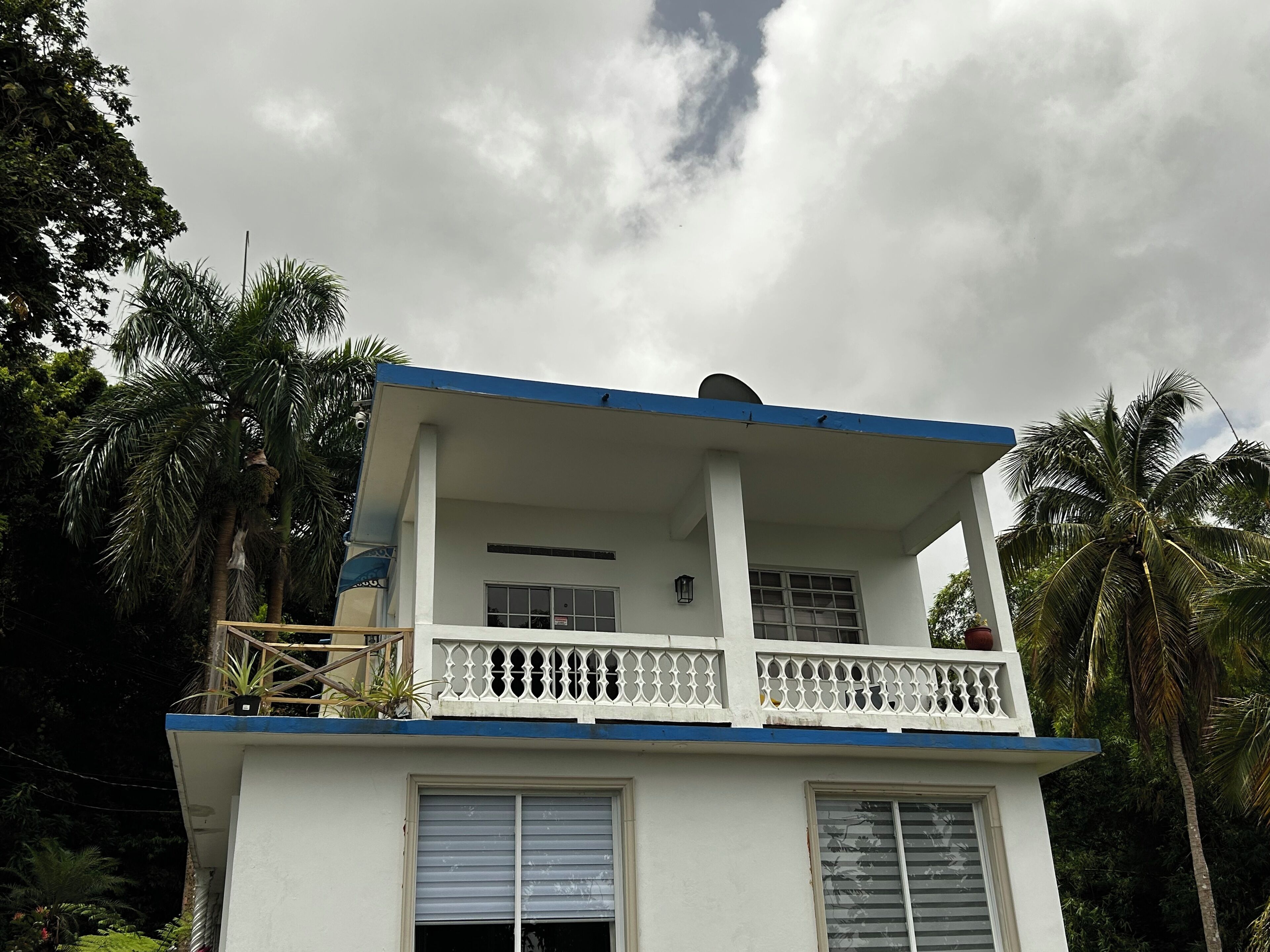 A two-story building with a balcony, surrounded by palm trees.