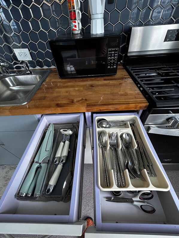 Une cuisine équipée d’un four à micro-ondes, d’une cuisinière et d’un tiroir avec un organiseur contenant des ustensiles.