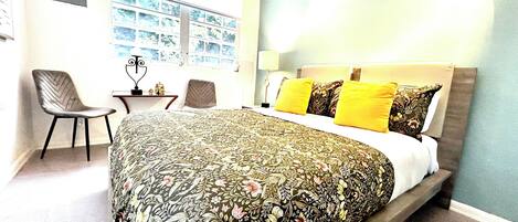 A bedroom with a large bed, a desk, and a chair.