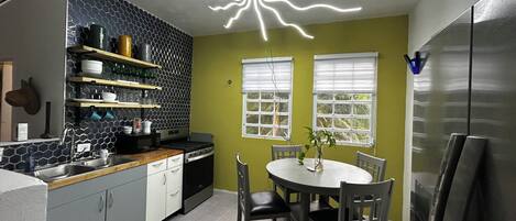 A modern kitchen with a central island, a dining table with chairs, and a unique ceiling light fixture.