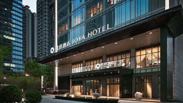 A modern hotel with a prominent sign, large windows, and a well-lit entrance. - JOYA Hotel Chengdu Taikoo Li IFS (Chengdu)