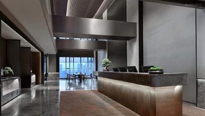 A modern reception area with a reception desk, seating area, and large windows providing natural light. - JOYA Hotel Chengdu Taikoo Li IFS (Chengdu)