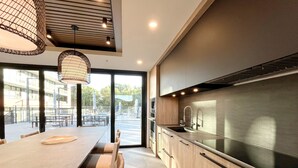 A modern kitchen with a large island, stainless steel appliances, and a view of the outdoor patio area. - New Luxury Beachfront Escape with Pool and Hottub (Kelowna)