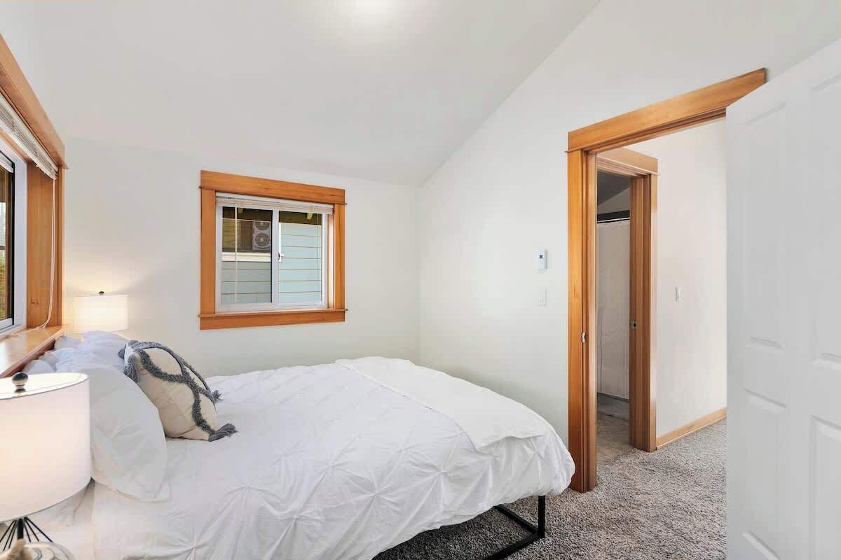 Een slaapkamer met een bed, een raam, een deur en een lamp.