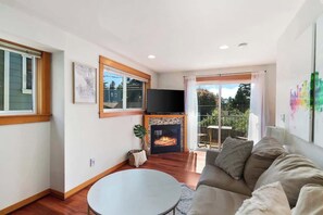 Una sala de estar con chimenea, televisor y sofá.