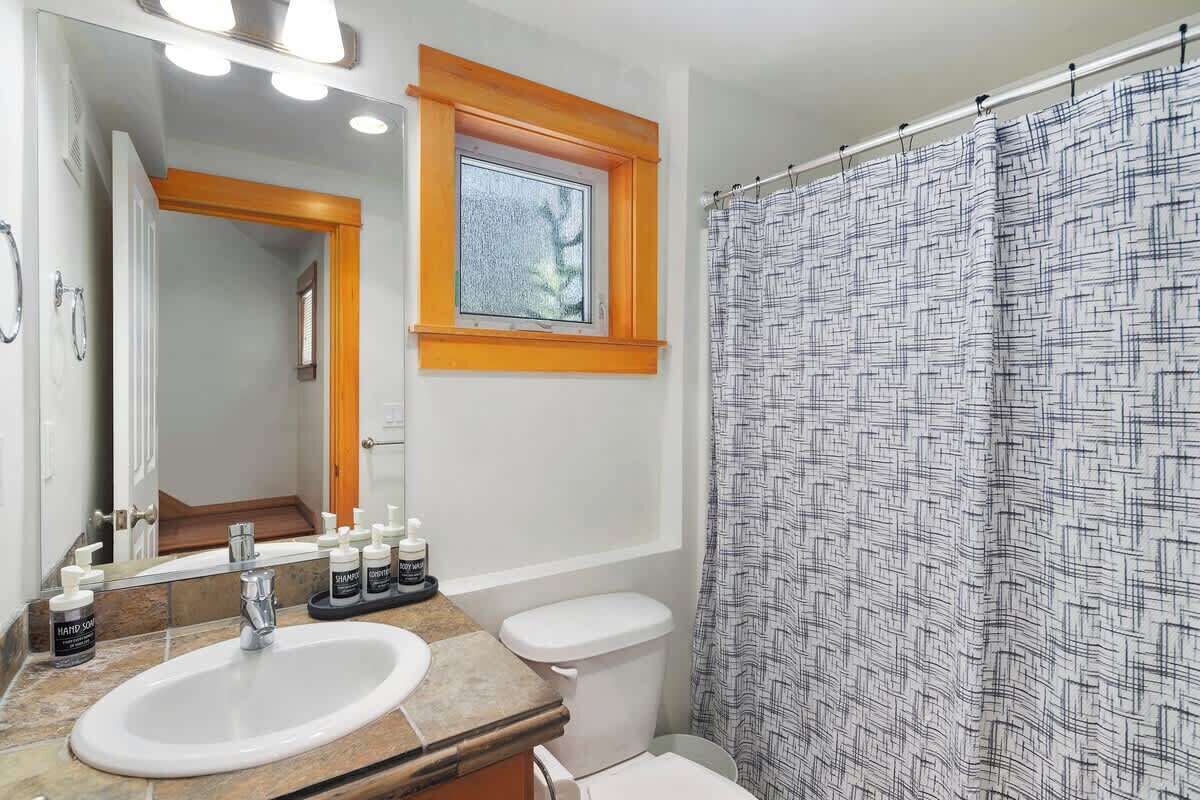 A bathroom with a sink, mirror, and shower curtain.