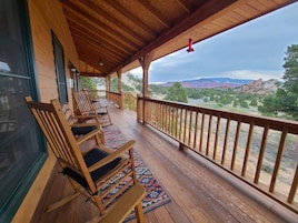 Una terraza de madera con mecedoras y vistas a un cañón.