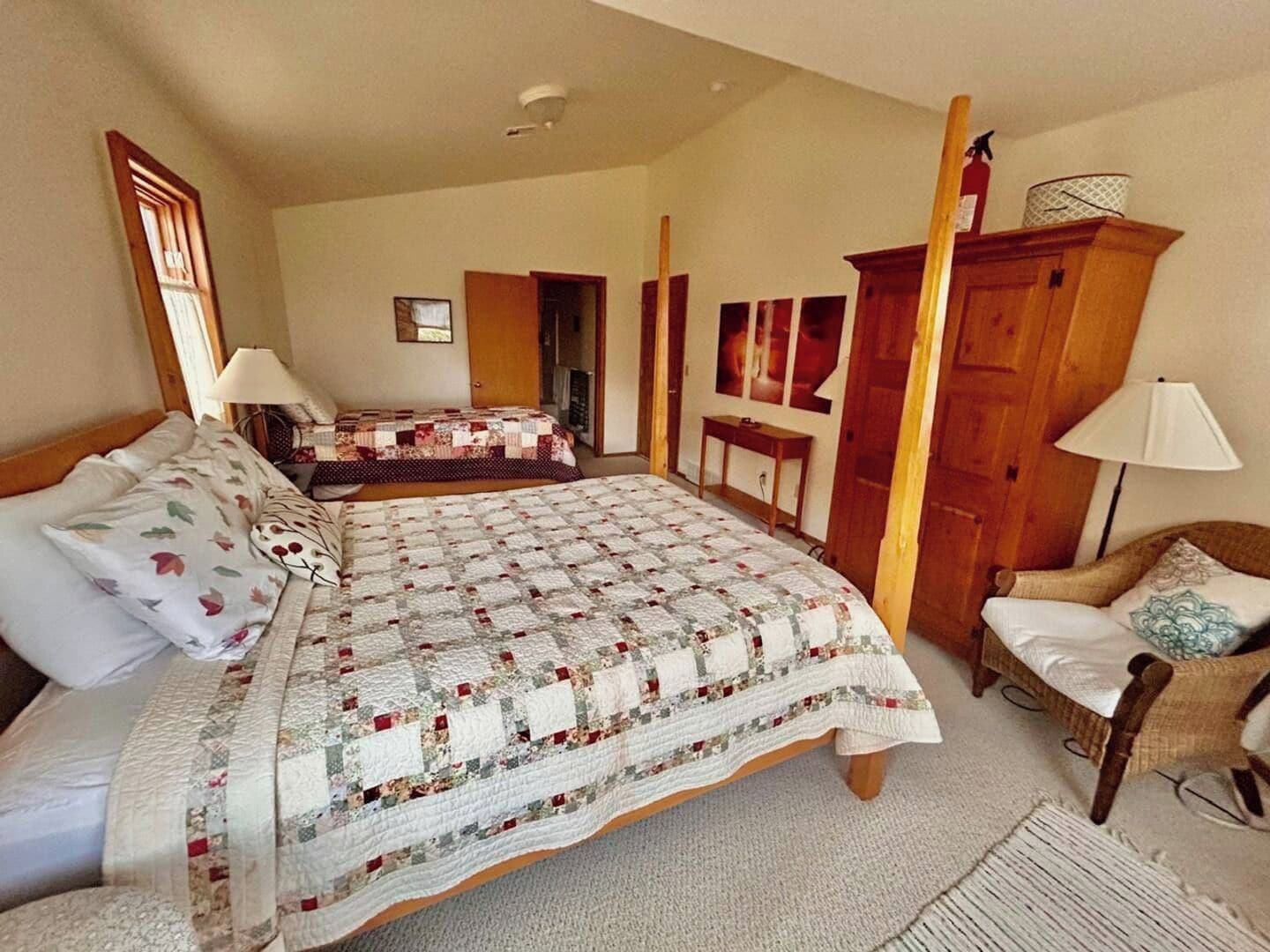 A bedroom with a large bed, a smaller bed, a chair, and a wardrobe.