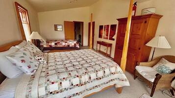 A bedroom with a large bed, a smaller bed, a chair, and a wardrobe.