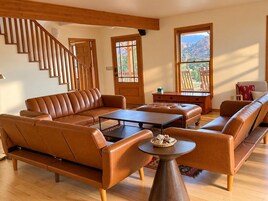Una sala de estar moderna con un sofá de cuero marrón, una mesa de centro y una escalera de madera.
