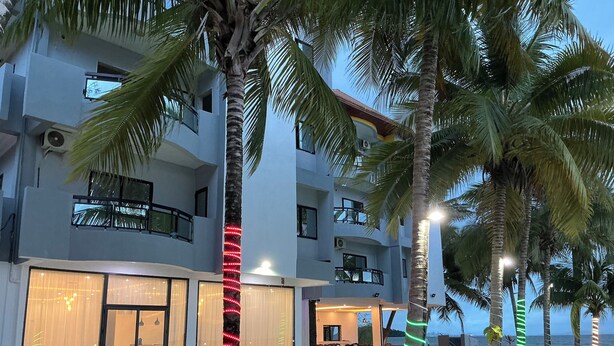 A modern hotel with multiple floors, large windows, and a covered outdoor seating area. - Fanaseti (Conakry)
