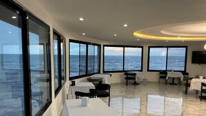 A restaurant with large windows offering ocean views, marble flooring, and modern decor. - Fanaseti (Conakry)