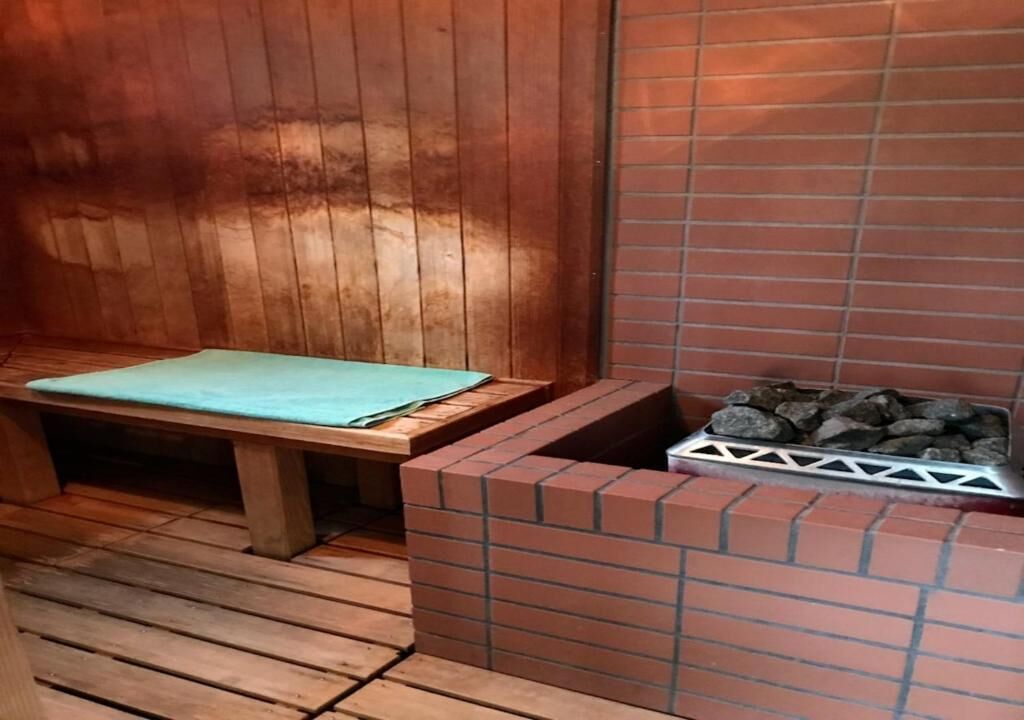 A wooden bench with a green cushion, a brick fireplace, and a stone fire pit.