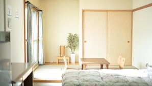 Een traditionele Japanse slaapkamer met tatami vloerbedekking, een lage houten tafel, een bankje en een schuifdeur van shoji papier.