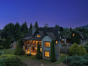 A large house with a stone fireplace, a covered porch, and a stone exterior.