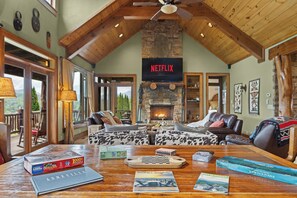 A cozy living room with a fireplace, leather sofas, a wooden coffee table with puzzles, and a Netflix sign.