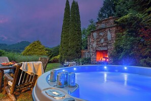 Una piscina con una estructura de piedra y una fuente de fuego, rodeada de follaje.