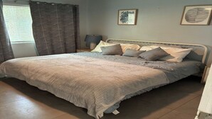 A bedroom with a large bed, a bedside table with a lamp, and two framed pictures on the wall. - Charming Studio apartment in delightful Pompano Beach 1 block from the ocean (Pompano Beach)
