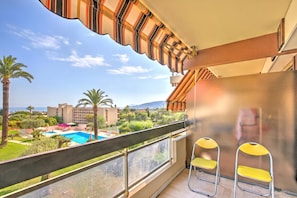 Un balcon avec vue sur une piscine, des palmiers et des bùtiments situés au loin.