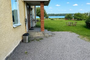 Een gebouw met een oprit van grind, leidend naar een overdekte veranda met zitplaatsen.