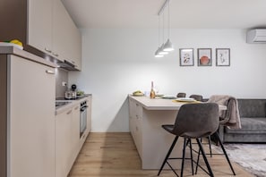 Una cocina moderna con una isla central, un área de comedor con un sofá gris y una pared con tres obras de arte enmarcadas.