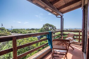 A wooden balcony with a view of a road and greenery.