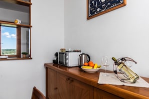 Une cuisine équipée d’un grille-pain, d’une bouilloire et d’un saladier rempli de fruits, posé sur le plan de travail.