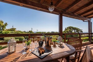 A wooden deck with a table set for dining, a metal bucket, and a lantern.