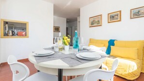 A dining area with a round table, white chairs, and a yellow sofa. - Una Finestra Sul Porto, Alghero, Italy (Alghero)
